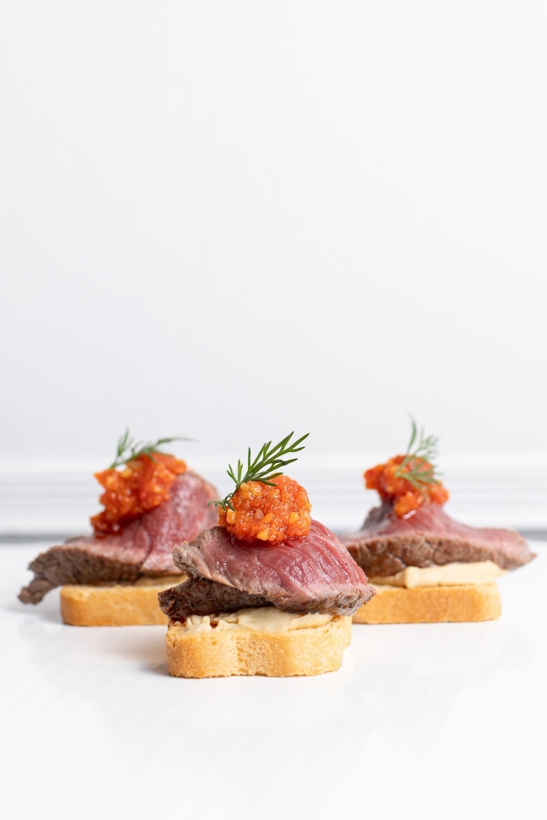 A close up of three appetizers on a white plate.