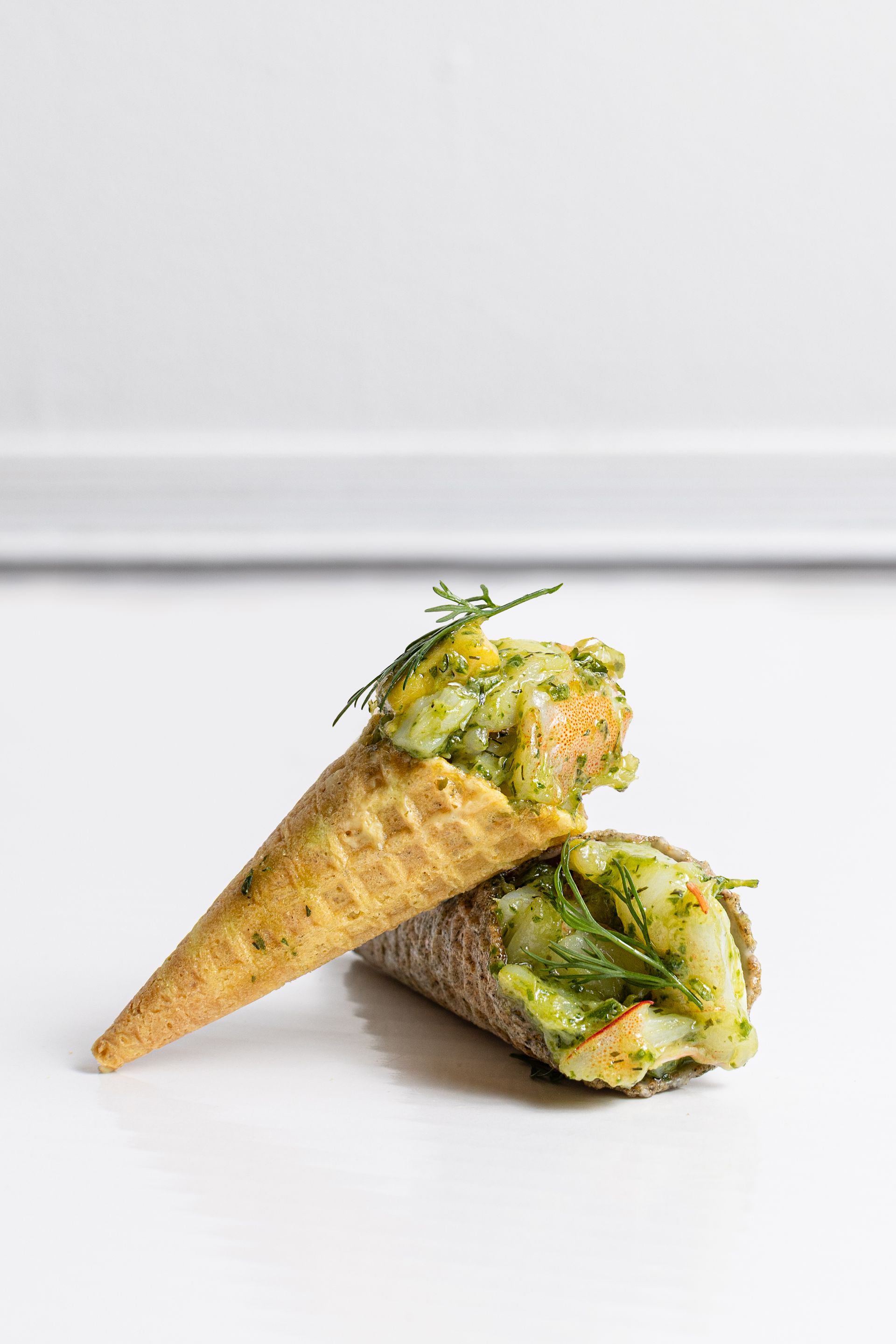 A close up of two ice cream cones filled with food on a table.