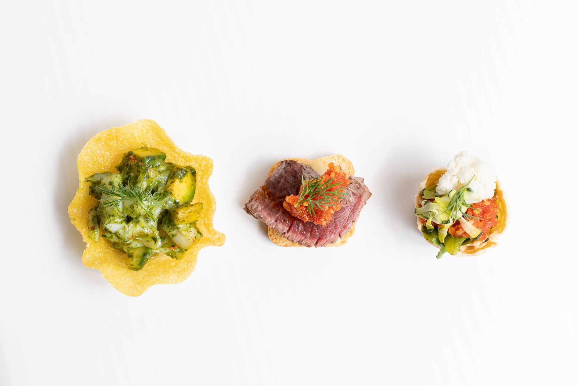 Three different types of food on tortilla chips on a white surface.
