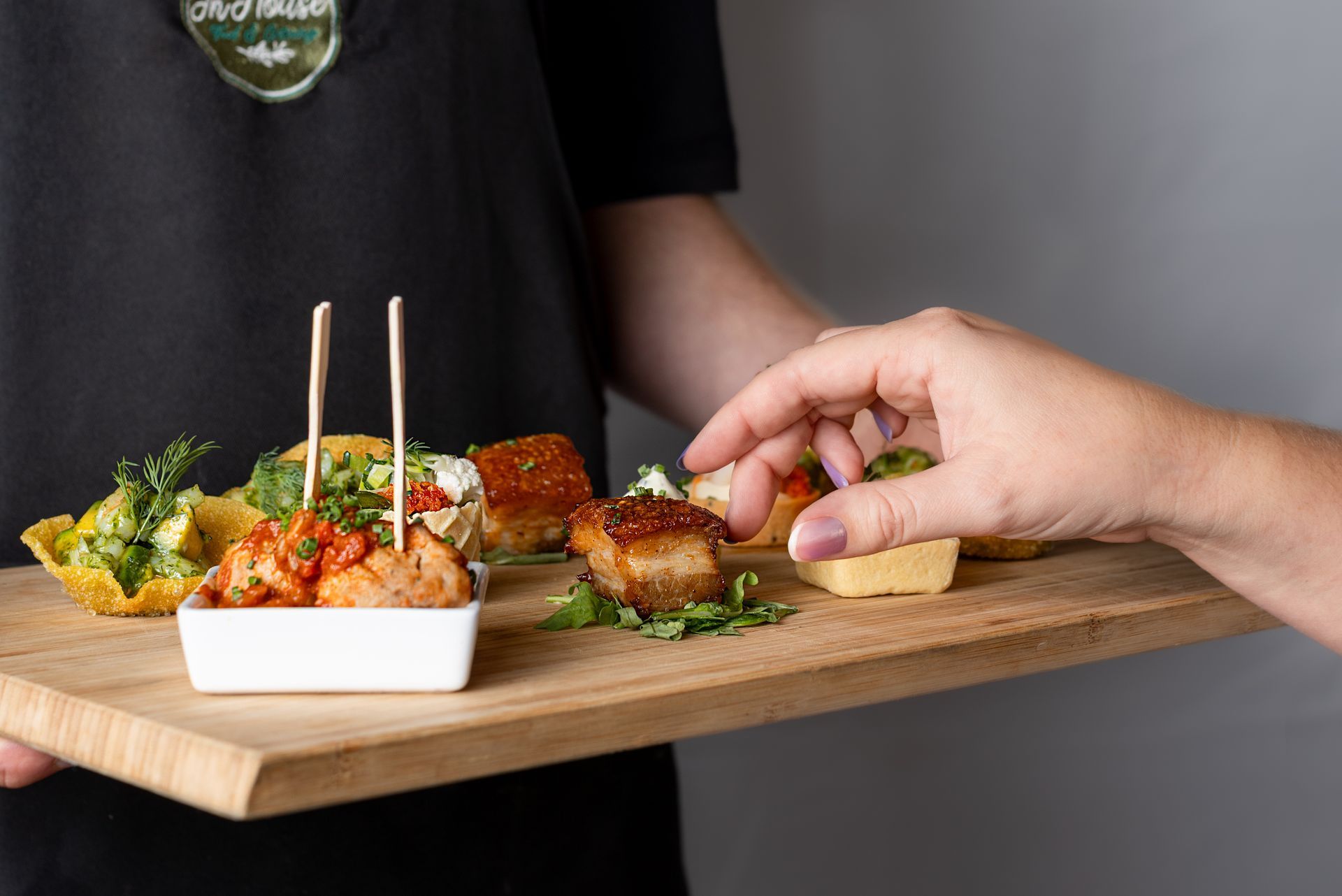 A person is holding a wooden cutting board with a variety of food on it.