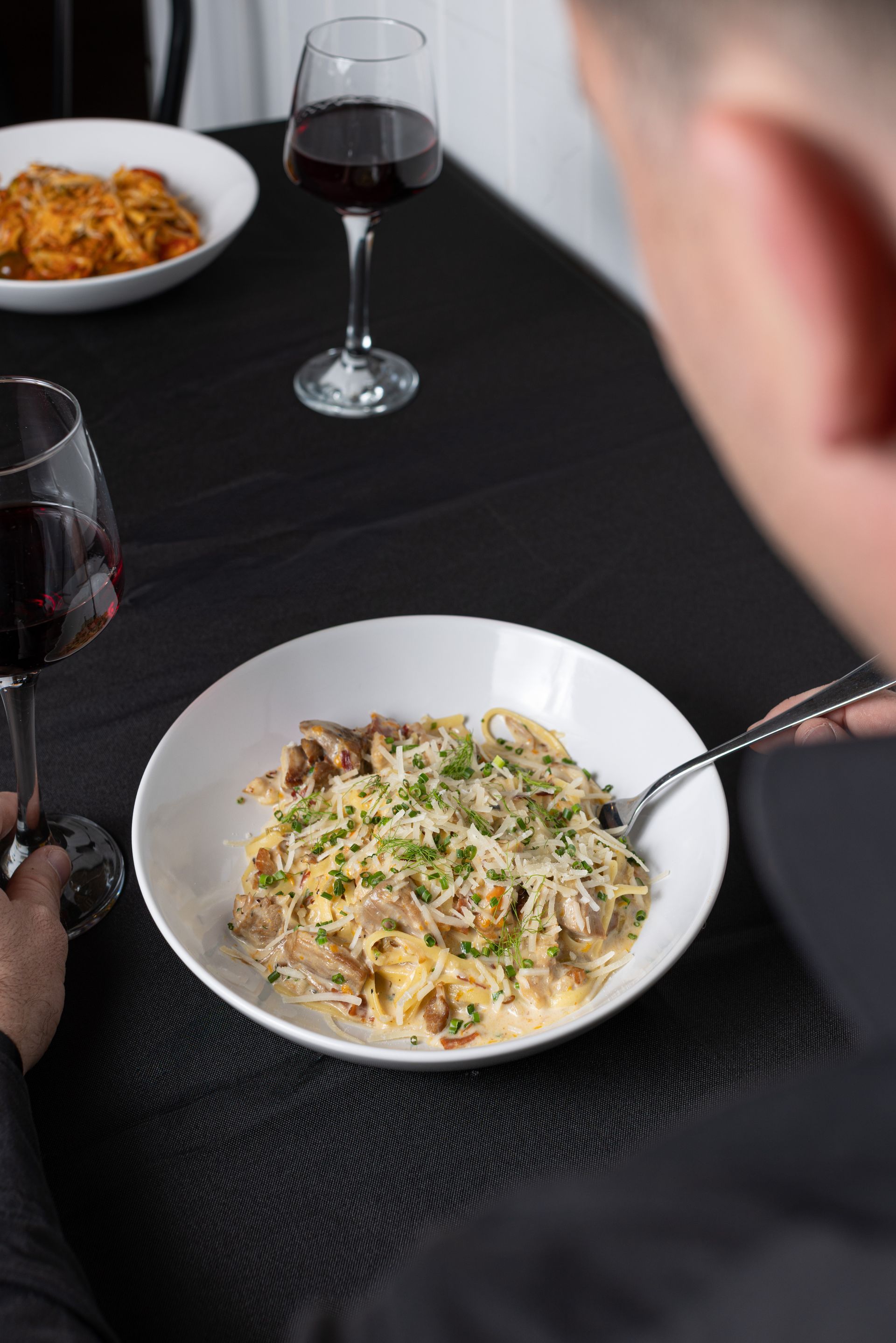 A man is sitting at a table with a plate of food and a glass of wine.