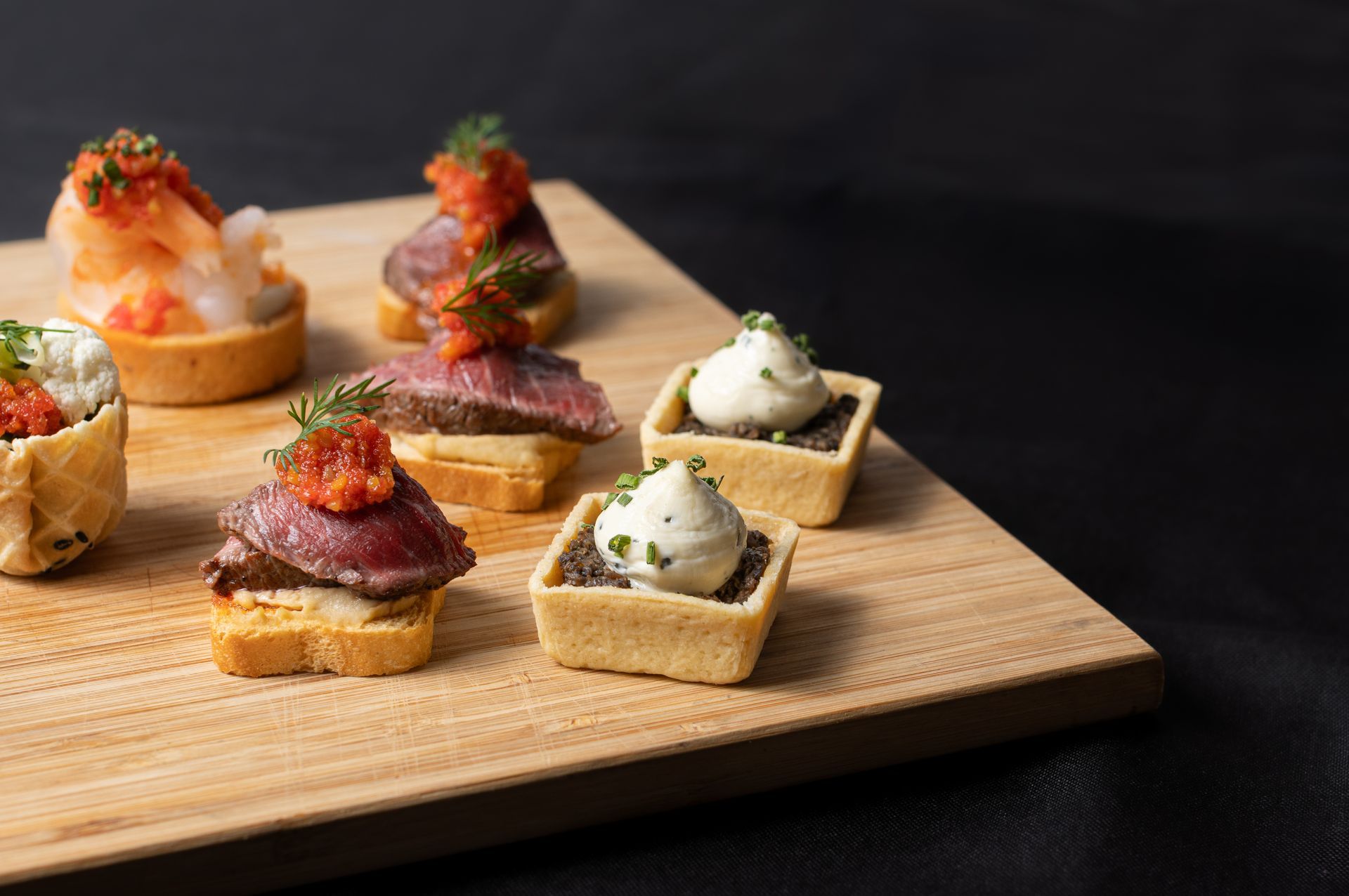 A wooden cutting board topped with a variety of appetizers.
