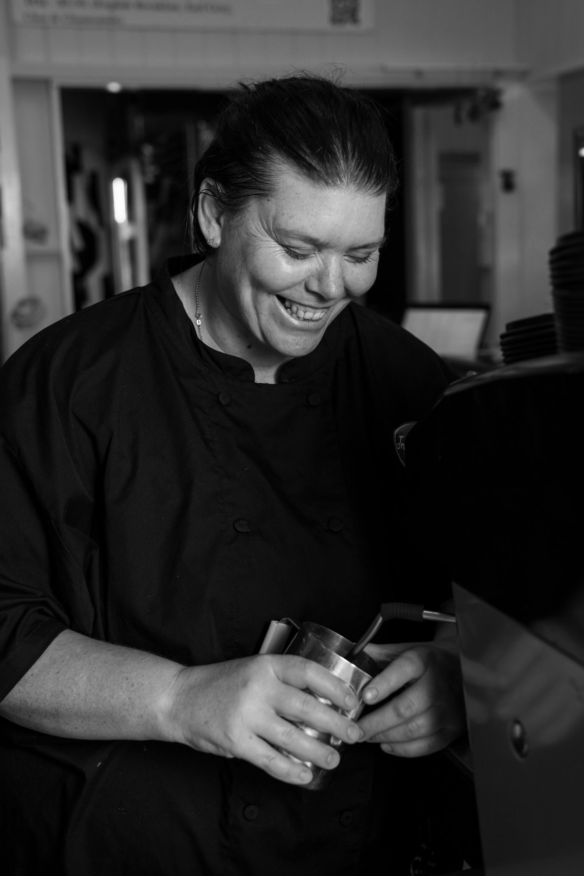 A black and white photo of a woman holding a cup and smiling.