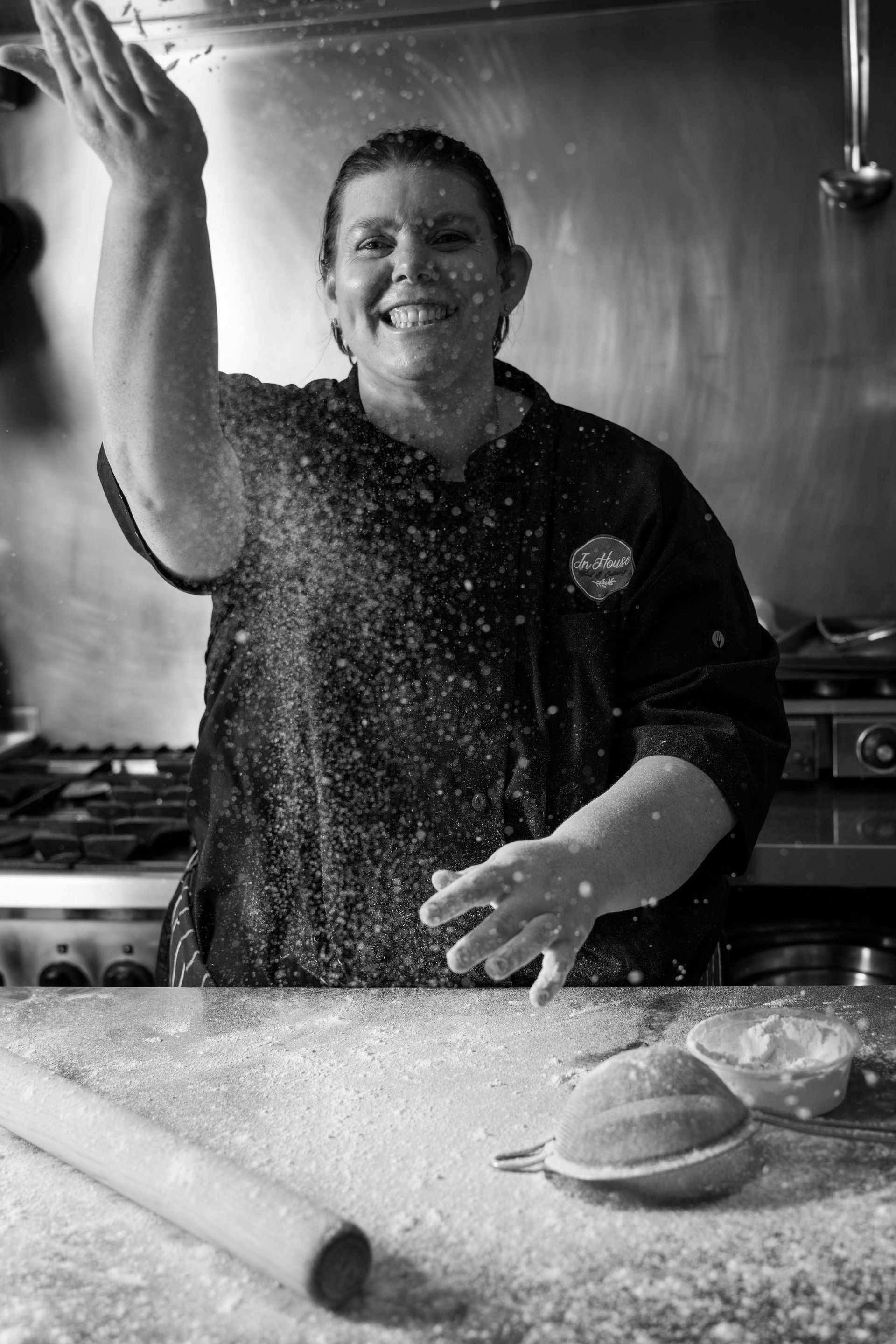 A woman is smiling while standing at a counter in a kitchen.