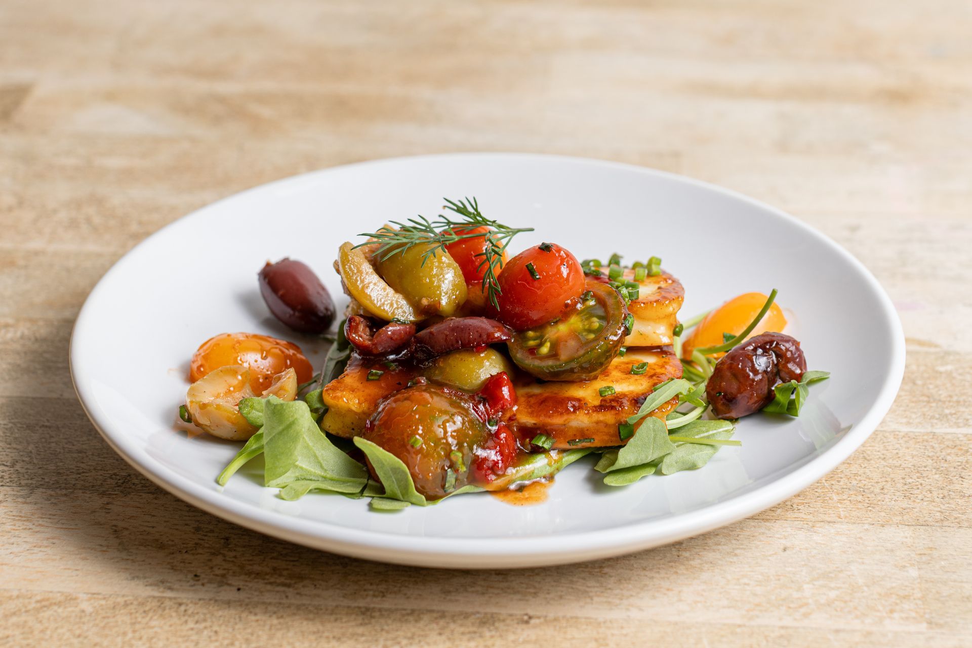 A white plate topped with a salad of vegetables on a wooden table.
