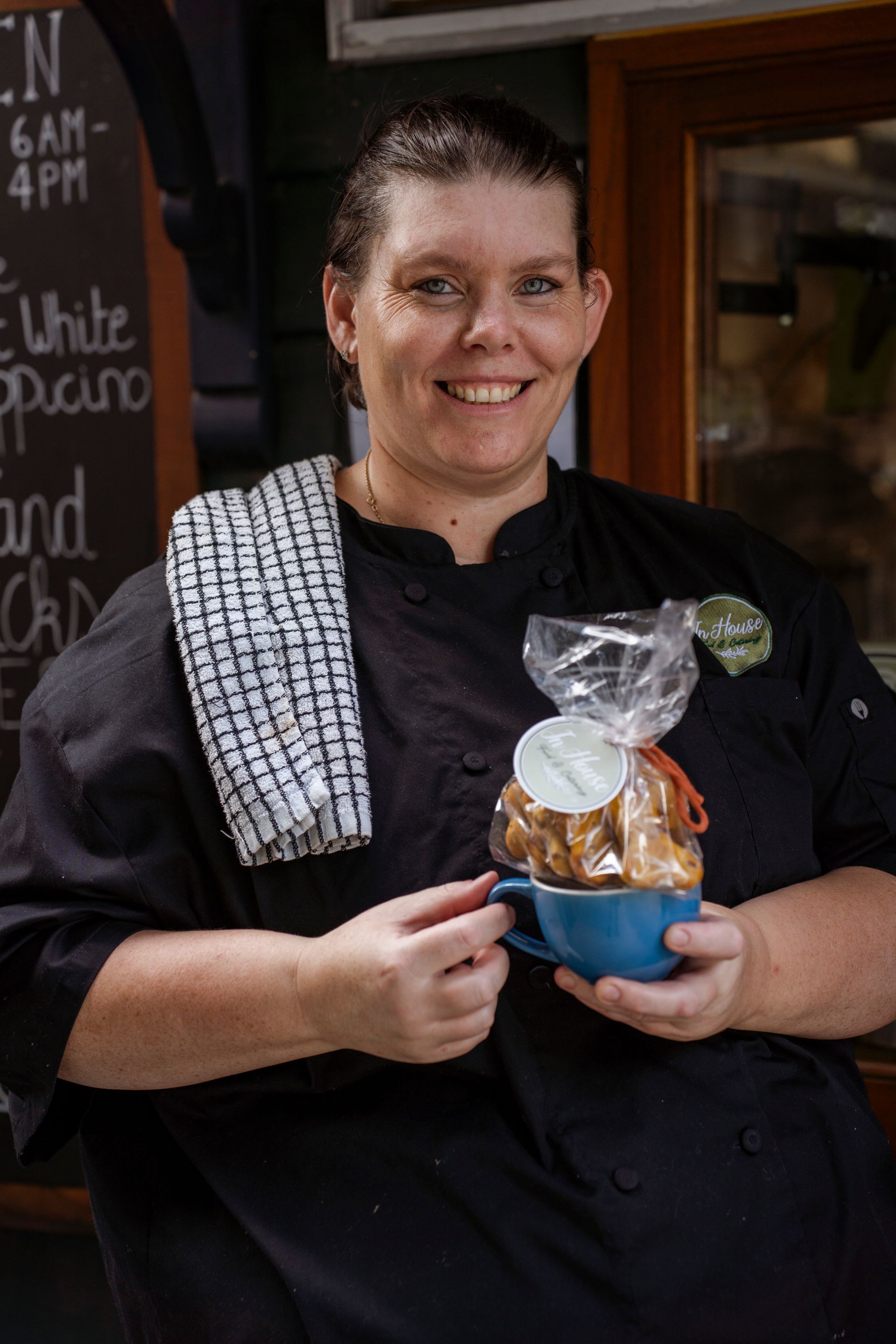 A woman is holding a cup of coffee and a bag of cookies.