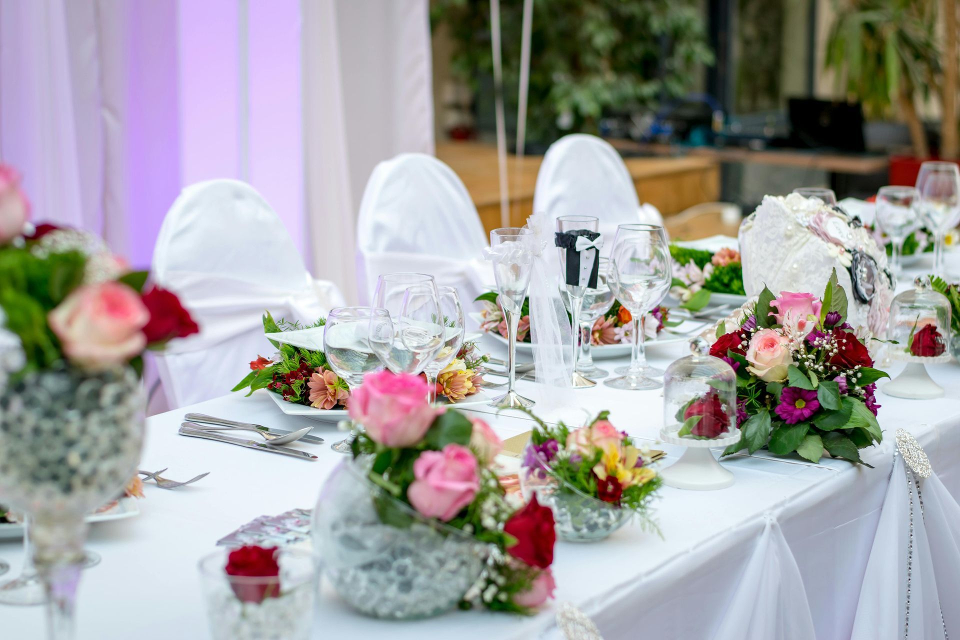 A long table set for a wedding reception with flowers on it.