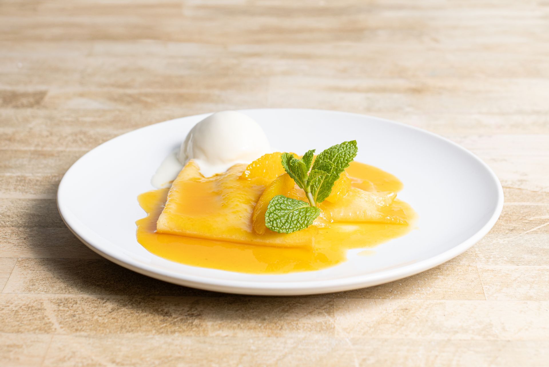 A white plate topped with a dessert and ice cream on a wooden table.