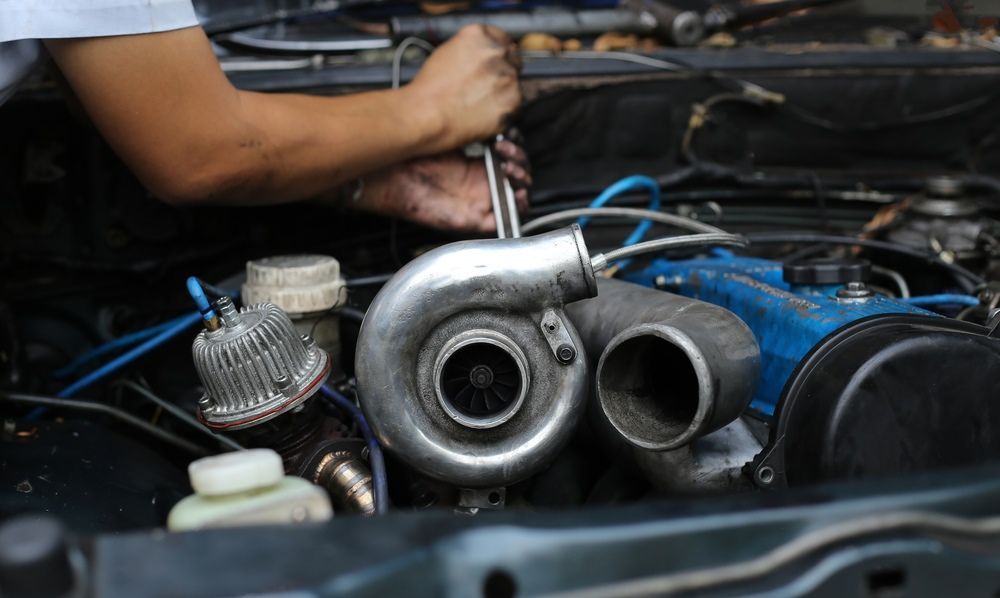 A Man Is Working On A Car Engine With A Wrench — Gympie Diesel & Dyno Centre in Glanmire, QLD