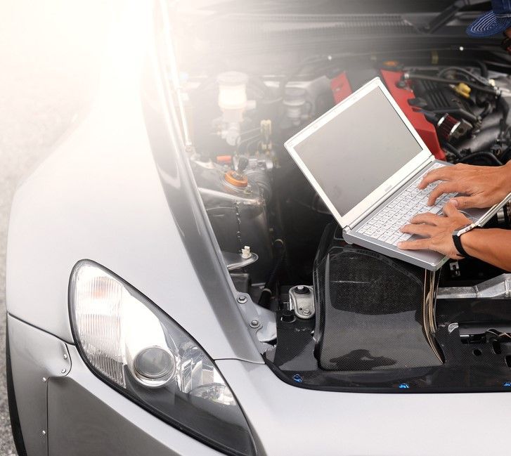A Person Is Using A Laptop Computer Under The Hood Of A Car — Gympie Diesel & Dyno Centre in Glanmire, QLD