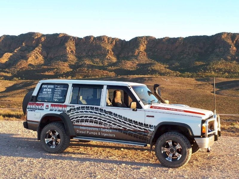 A White Jeep Is Parked In The Desert With Mountains In The Background — Gympie Diesel & Dyno Centre in Glanmire, QLD