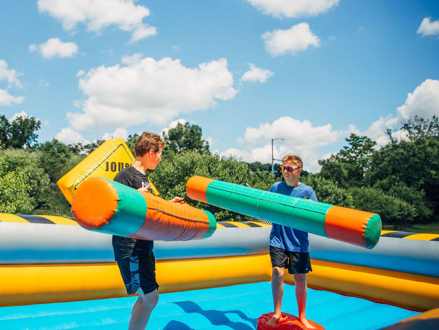 Two young boys are playing a game on a bouncy castle.