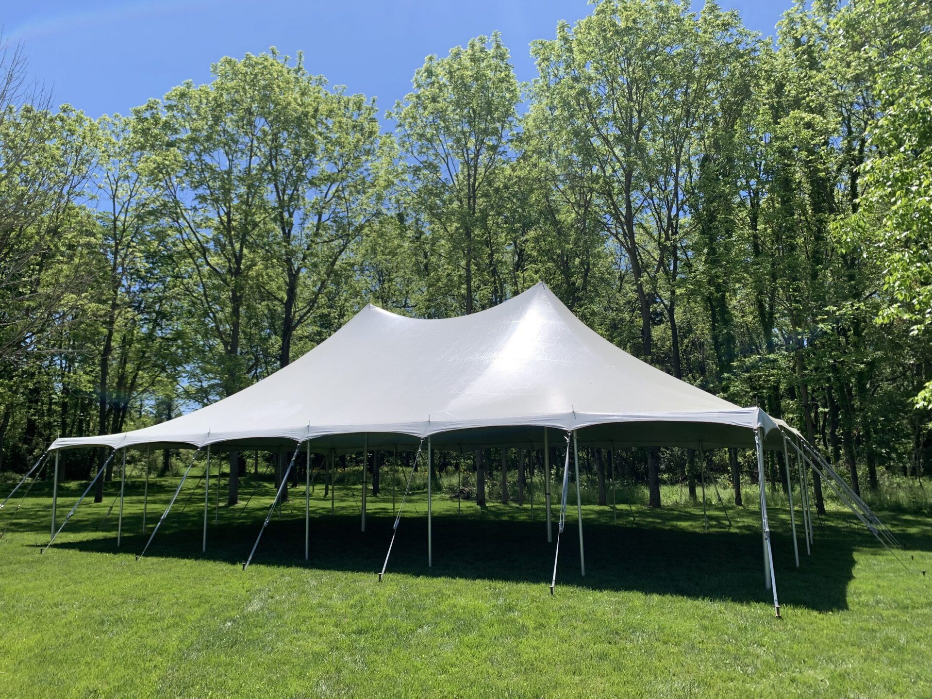 A large white tent is sitting in the middle of a grassy field.