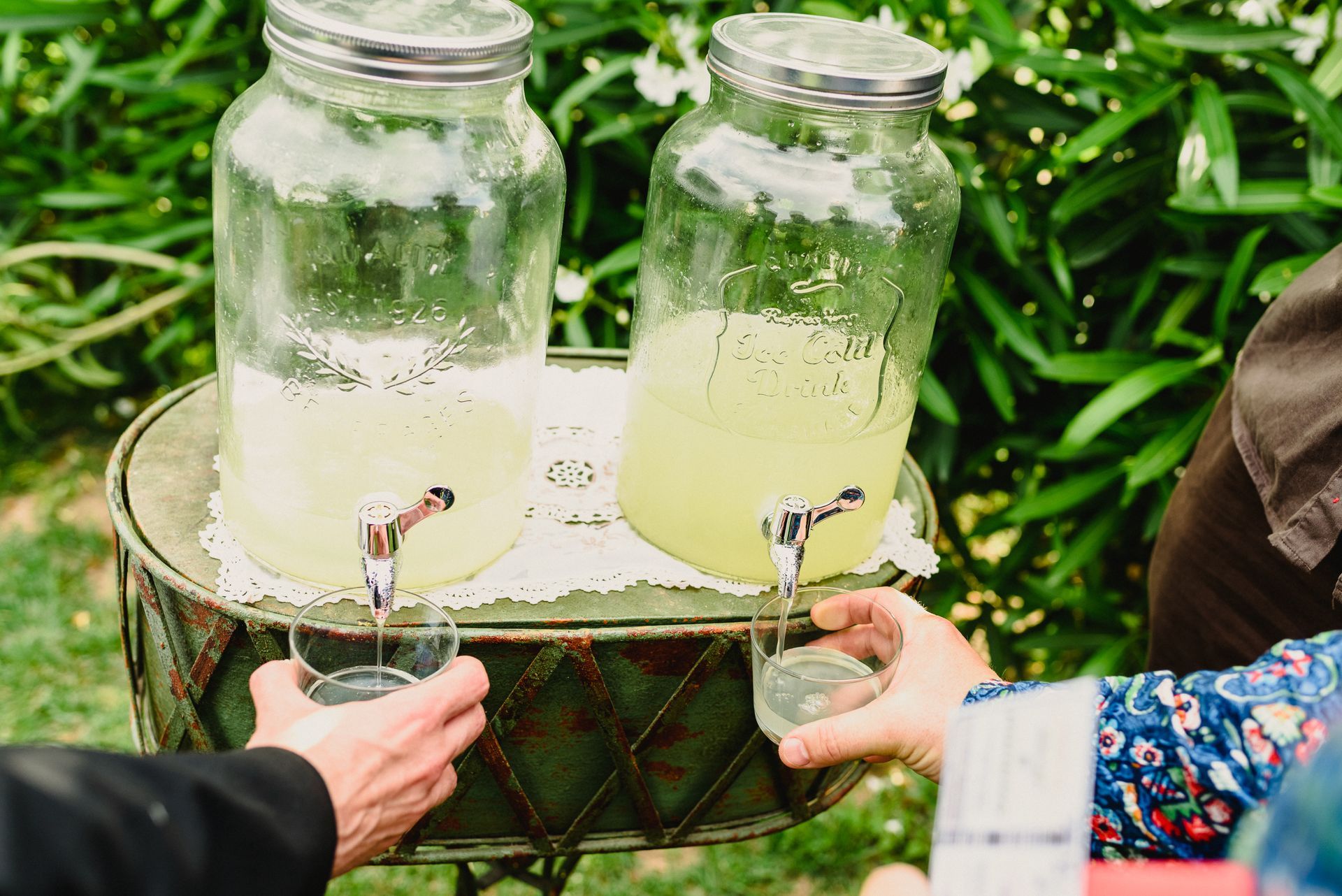 A group of people are standing around a table holding glasses of lemonade.