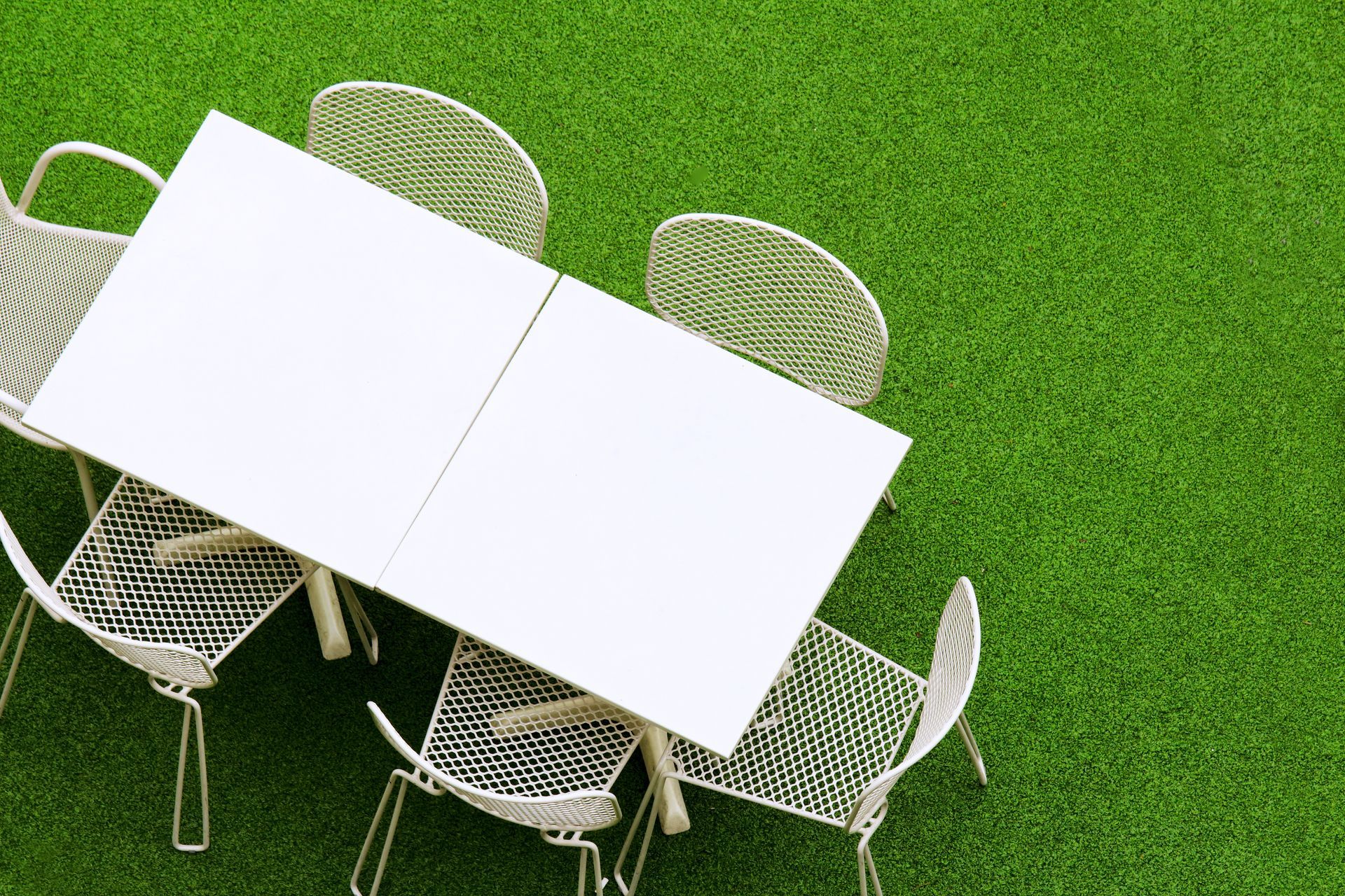 A white table and chairs are sitting on top of a lush green lawn.