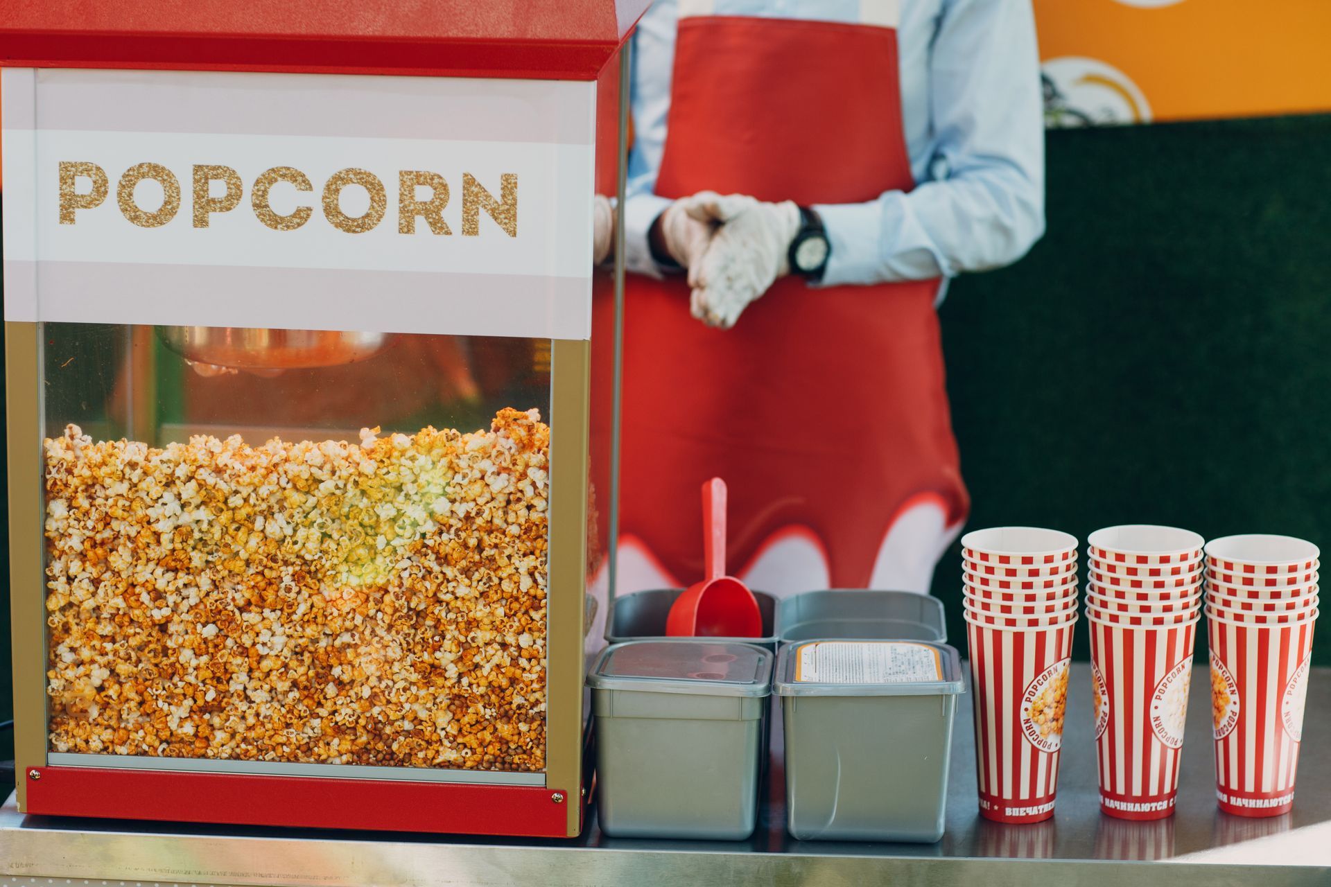 A man is standing in front of a popcorn machine.