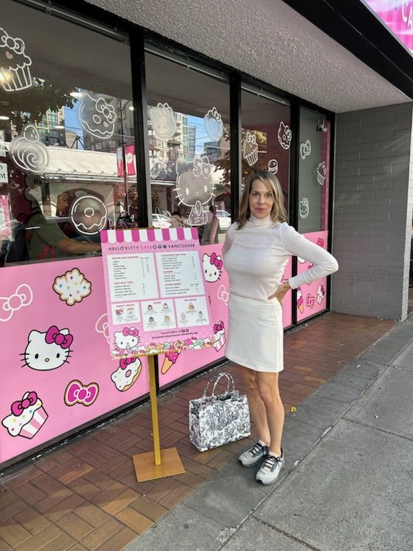 Woman in white outfit stands in front of a caffe