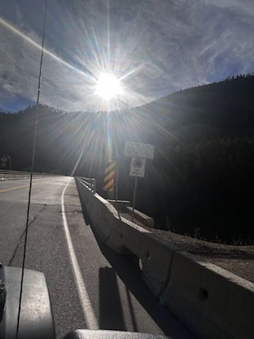 Road curving toward a bright sun over a mountain