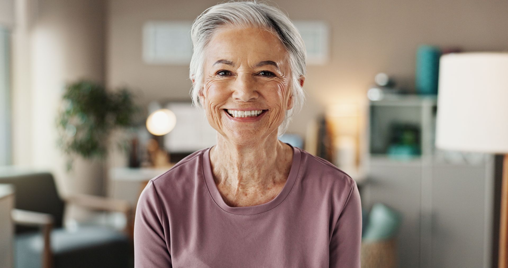 Smiling older woman in a pink top indoors