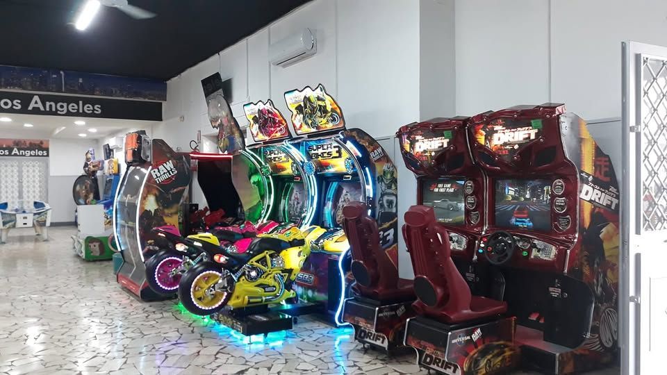 Un mucchio di videogiochi arcade sono allineati in una stanza.