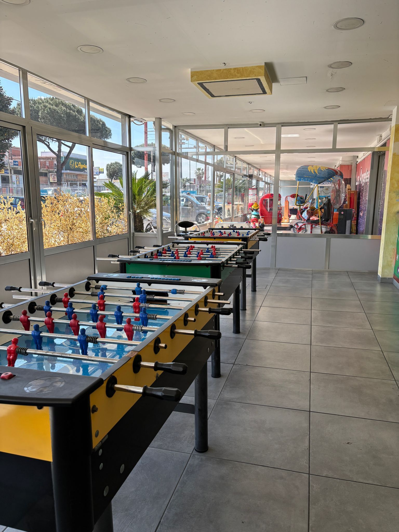 Una fila di tavoli da calcio balilla in una stanza con molte finestre