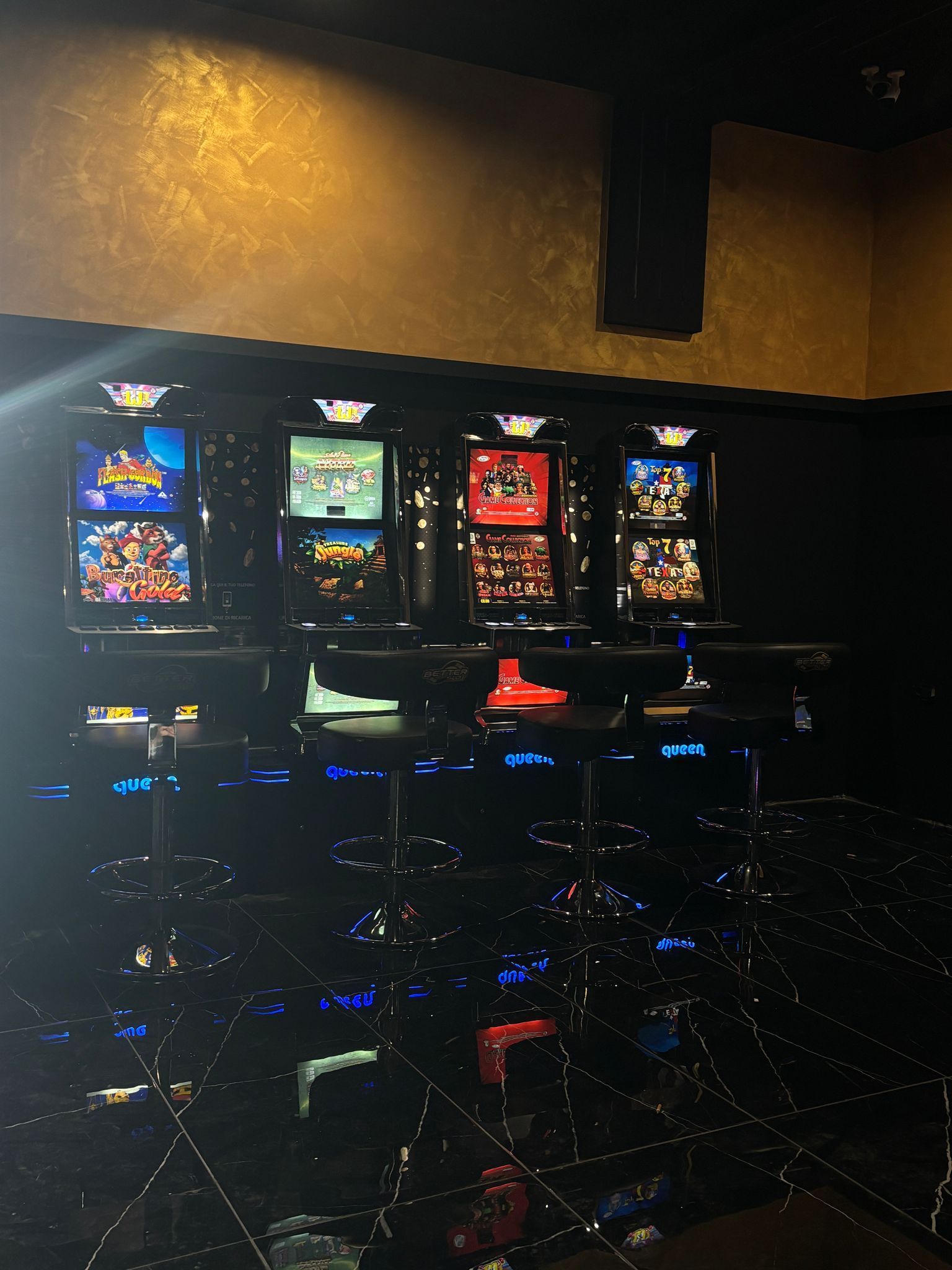 Una fila di slot machine sono allineate in una stanza buia.