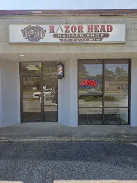 Storefront of Razor Head Barber Shop with red neon “OPEN” sign above the entrance