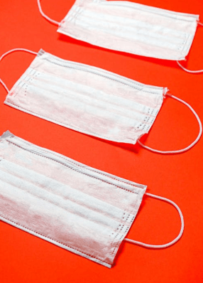 three white face masks are lined up on a red background .