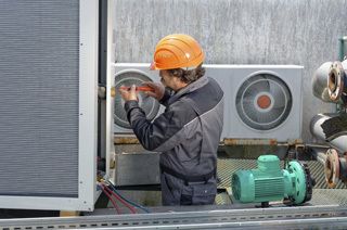 Man performing repairs on a commercial heating & cooling unit