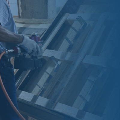 Worker spray-painting a tilted window frame with a hose in an industrial setting