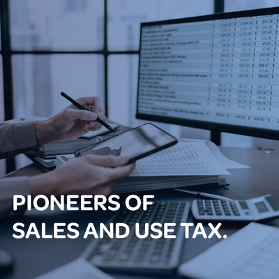 Person writing at a desk beside a computer showing sales tax data, with text “PIONEERS OF SALES AND USE TAX.”