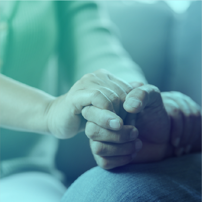 Two hands clasped together in a comforting gesture with a soft blue-green tint