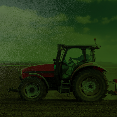 Red tractor in a field under a cloudy green-tinted sky.