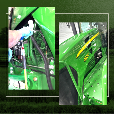 Bright green John Deere tractor close-up with someone spraying or cleaning a metal component