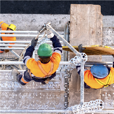 Construction workers on scaffolding securing a rope and board at a building edge