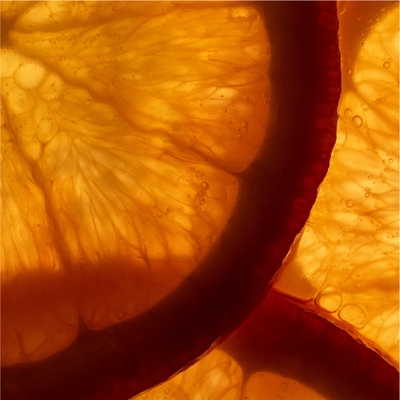 Orange citrus slices seen in close-up, with bright translucent pulp and dark red rind edges.