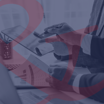 People reviewing charts and a calculator at a desk, with a pen and tablet in hand.