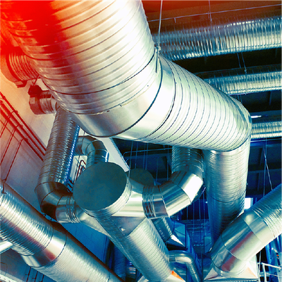 Metal ventilation ducts and pipes in an industrial ceiling, lit with red and blue reflections