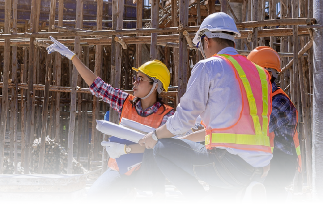 Construction workers in hard hats reviewing plans at a building site