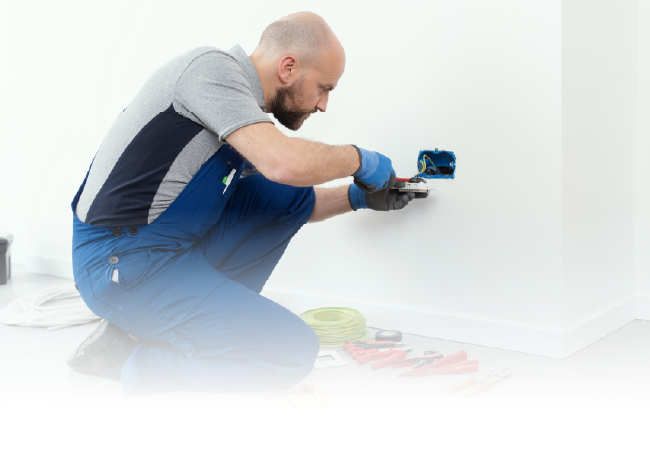 Person kneeling, painting a white wall with a blue roller near the floor