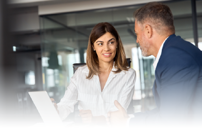 Two people talking in a bright office, smiling over a laptop