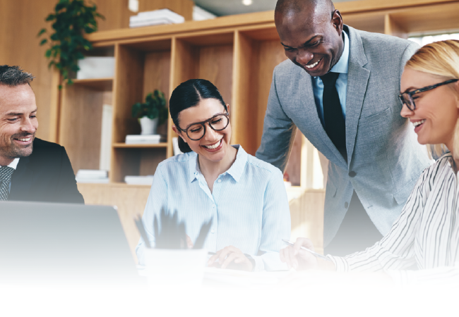 Colleagues smiling around a laptop in a bright office meeting room