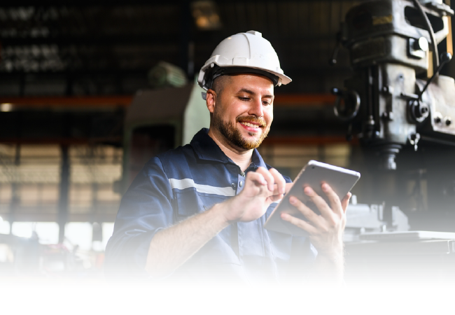 Worker in a hard hat using a tablet in an industrial facility