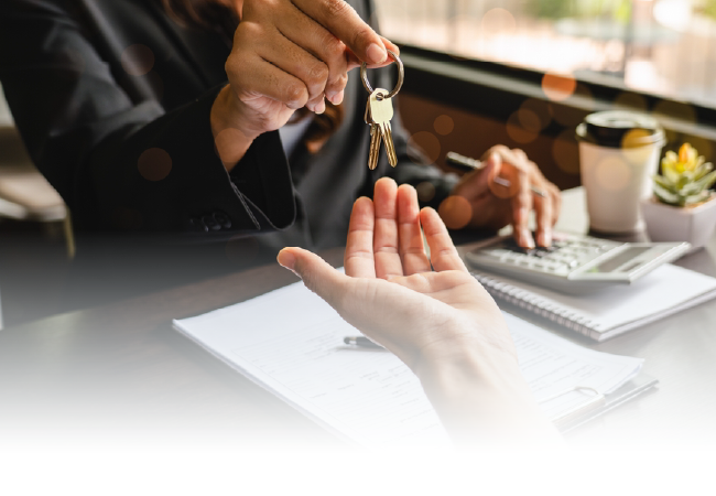 Hand giving a ring to an outstretched hand at a desk with laptop and coffee