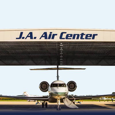 Jet centered in front of J.A. Air Center hangar, with open canopy and engines visible