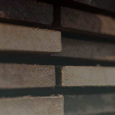Stacked weathered wooden planks in a dim, close-up view