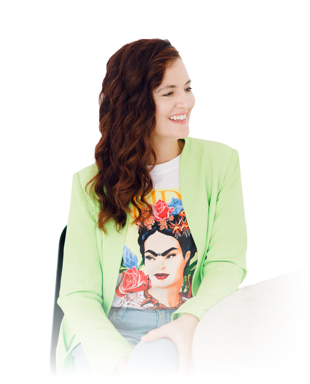 Woman in a light green blazer smiling and looking to the side, wearing a Frida Kahlo T-shirt.