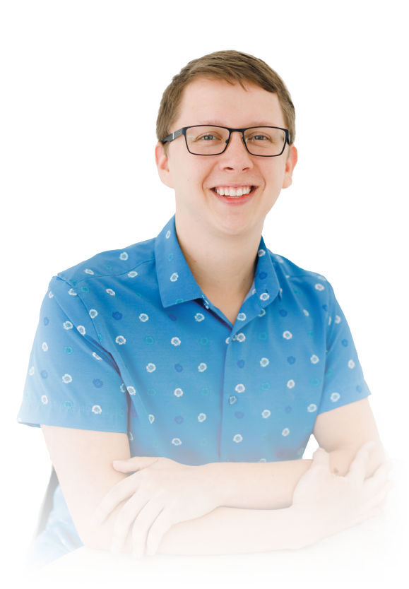 Smiling person in glasses wearing a blue patterned shirt with arms crossed on a white background