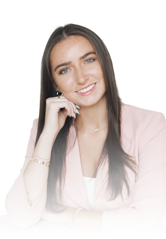 Smiling woman in a light pink blazer with long brown hair, resting her chin on her hand against a white background