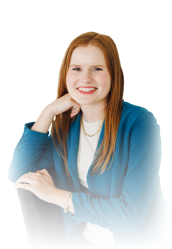 Smiling person with red hair in a blue blazer, resting chin on hand against a white background